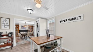 A kitchen with a wooden table, a wall-mounted sign reading 'SUPER MARKET,' and a ceiling fan. - Historic Kings on Queen Cottage in Georgetown's Historic District, just 10 min to beach. (Georgetown)