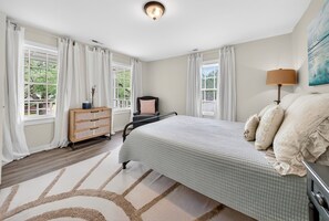 A bedroom with a bed, a dresser, a chair, a lamp, and a painting on the wall. - Historic Kings on Queen Cottage in Georgetown's Historic District, just 10 min to beach. (Georgetown)