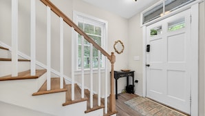 A staircase with wooden steps and white railings, a white door with a small window, and a rug on the floor. - Historic Kings on Queen Cottage in Georgetown's Historic District, just 10 min to beach. (Georgetown)