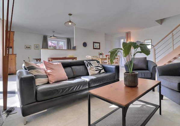 A modern living room with a leather sofa, a coffee table, and a potted plant. - L'Escale du Grand Bois (QUEBRIAC)