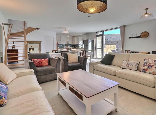 Un salon moderne avec un canapé, un fauteuil, une table basse et un escalier.