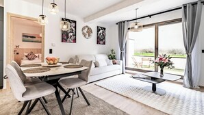 Ein modernes Wohnzimmer mit Essbereich, großen Fenstern und Kunstwerken an den Wänden.