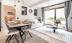 Ein modernes Wohnzimmer mit Essbereich, großen Fenstern und Kunstwerken an den Wänden.