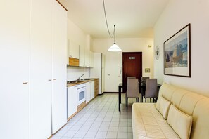 A compact kitchen with white cabinets, a wooden countertop, and a dining area with a beige sofa and table. - El Sol by Casa di Marco (Campo Verde)