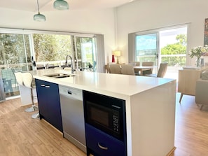 A modern kitchen with a dishwasher, a sink, and a dining area with a table and chairs.
