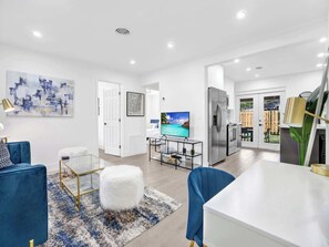 A modern living room with a TV, a dining area, and a kitchen. - Cool Blue - Designer 3BR Retreat (Fort Lauderdale)