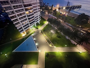 En hög byggnad med flera våningar, en central innergård med en pool och en bro i bakgrunden.