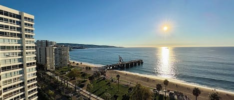 Un paisaje urbano costero con playa, muelle y edificios altos.
