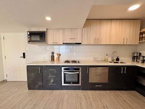 A modern kitchen with a microwave, oven, and dishwasher, wooden cabinets, and a stainless steel sink.