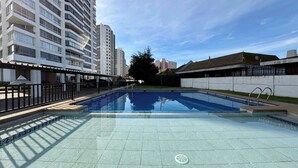 A swimming pool with a tiled deck, surrounded by high-rise buildings.
