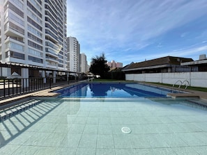 A swimming pool with a tiled deck, surrounded by high-rise buildings.