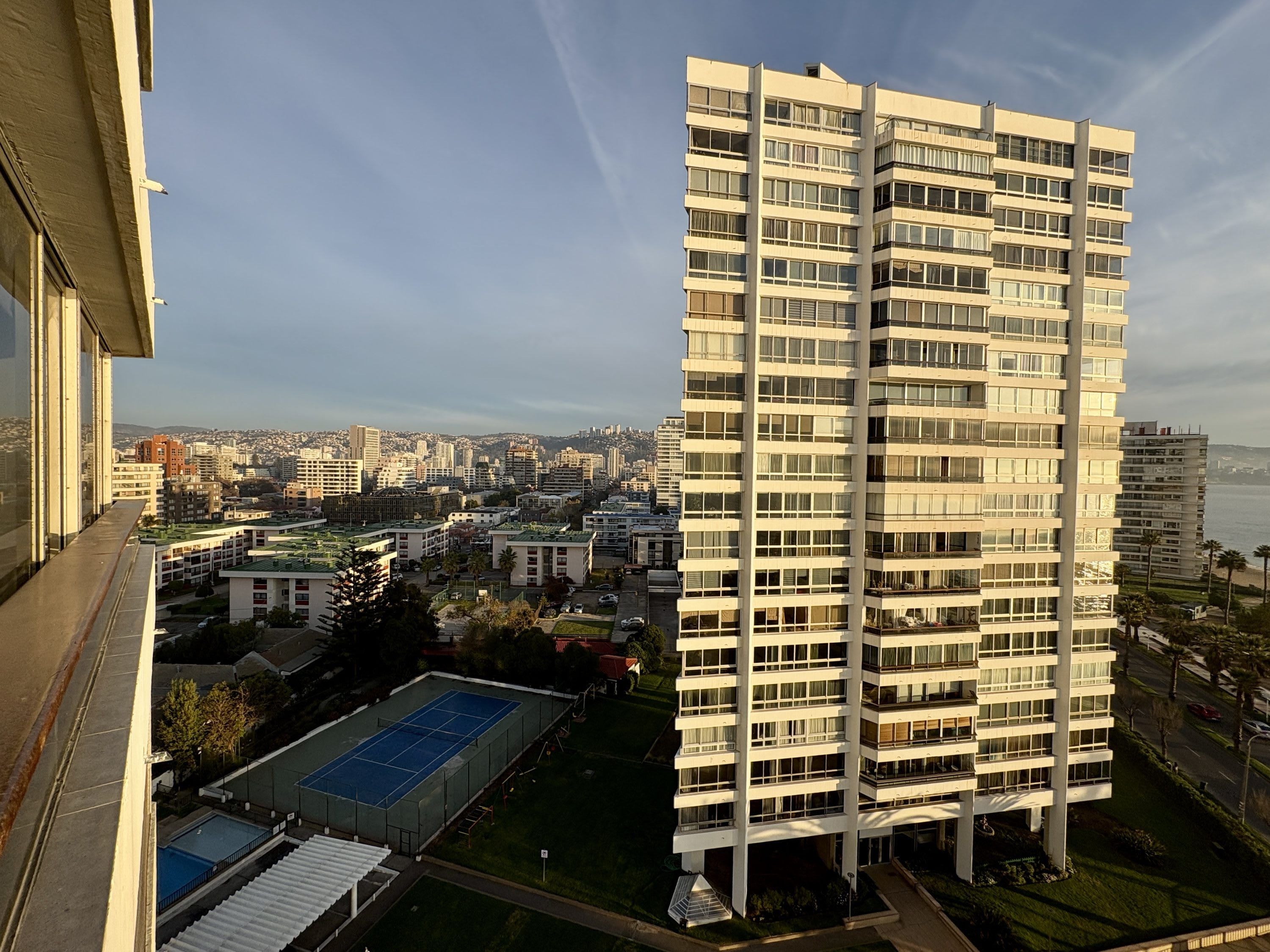 Un edificio alto con varios pisos, rodeado de otros edificios y un cielo despejado.