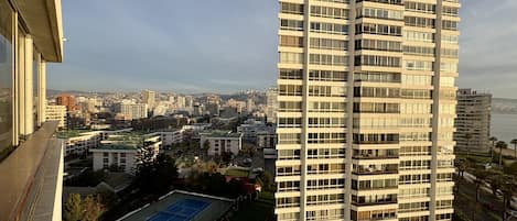 Un edificio alto con varios pisos, rodeado de otros edificios y un cielo despejado.
