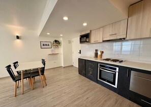 A modern kitchen with a dining area, featuring a microwave, stove, and cabinets.