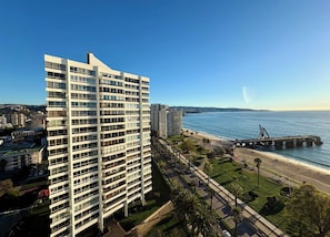 Ein Hochhaus mit mehreren Etagen, einer Strandpromenade und einem sich ins Meer erstreckenden Steg.