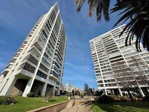 Deux immeubles de grande hauteur dotés de balcons, un ciel dégagé et une pelouse bien entretenue.