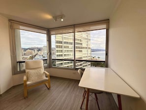 A room with a large window, a wooden chair, and a table.