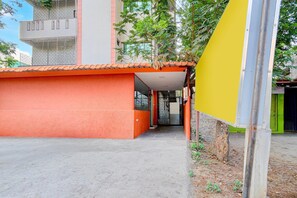 Un bâtiment à la façade rouge, avec une entrée bien visible et un arbre en arrière-plan.