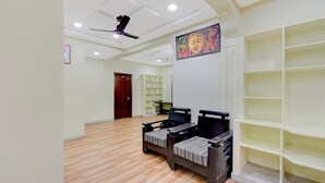 Una habitación con ventilador de techo, un cuadro de Buda y suelo de madera.