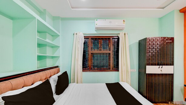 Un dormitorio con cama, ventana con cortinas, aire acondicionado y armario.