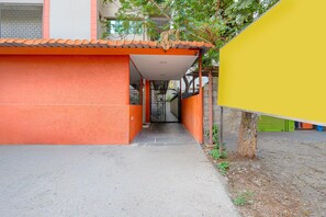 A narrow pathway leading to a building with a red facade and a yellow structure to the right. - Classic S Grand Residency (Hyderabad)