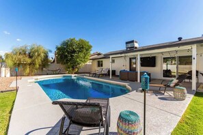 Ein Garten mit Swimmingpool, Liegestühlen und einer überdachten Terrasse.