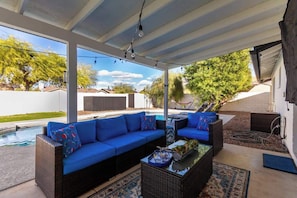 Eine Außenpatio mit Pool, einer blauen Sofagarnitur und einem Glastisch.