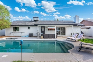 Ein Wohnhaus mit Swimmingpool, Sitzgelegenheiten im Freien und einer überdachten Terrasse.