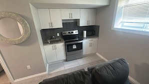 A compact kitchen with white cabinets, a black countertop, and a built-in oven.