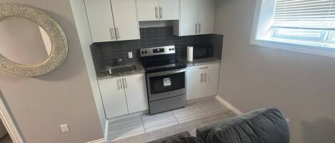 A compact kitchen with white cabinets, a black countertop, and a built-in oven.