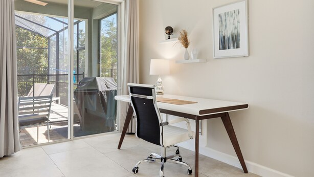 A modern office space with a desk, chair, and a view through a glass door to an outdoor area. - 7BR / 6BA w/ Private Pool / Solara Resort SO9051 (Kissimmee)