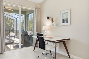 Ein moderner Arbeitsbereich mit Schreibtisch, Stuhl und Blick durch eine Glastür auf einen Außenbereich.