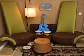 Ein Zimmer mit zwei grünen Sesseln, einer blauen Gitarre und einem Schlagzeug.