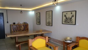 Un'area pranzo con tavolo e sedie in legno, un'opera d'arte appesa alla parete e una lampada a sospensione.