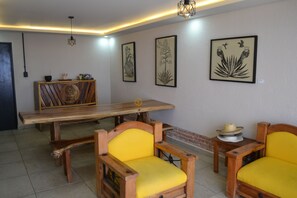 Ein Essbereich mit Holztisch und -stühlen, einem gerahmten Kunstwerk an der Wand und einer Hängeleuchte.