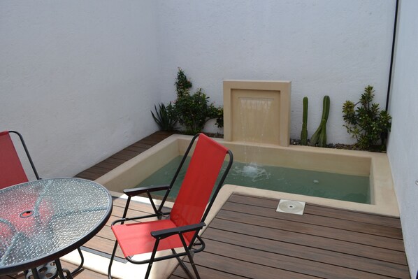 A patio area with a round glass table, two red chairs, a wooden deck, a small hot tub, and some cacti. - Renovated 5 Element house with small pool 15 minutes from downtown Oaxaca (Oaxaca de Juárez)