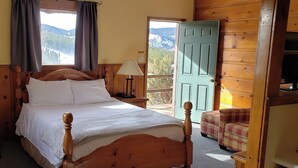 Una cama de madera en una habitación con vista a las montañas a través de una ventana.