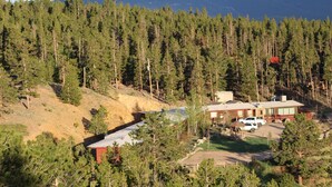 Un barrio residencial con una casa, un coche y una ladera cubierta de bosque.