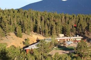 Un barrio residencial con una casa, un coche y una ladera cubierta de bosque.
