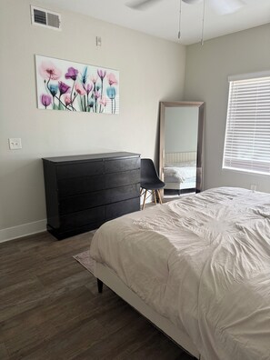 Ein Schlafzimmer mit Bett, Schminktisch, Spiegel und Bildern an der Wand.