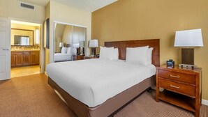 A hotel room with a large bed, a wooden nightstand, a mirror, and a bathroom visible through an open door. - Lakefront & Views! Hilton Suite in South Lake Tahoe (South Lake Tahoe)