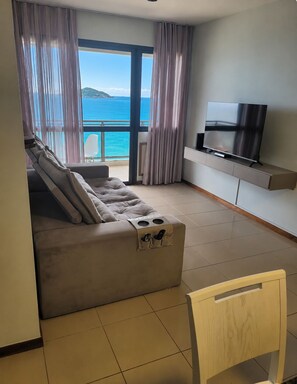 Ein modernes Wohnzimmer mit Sofa, Fernseher und Meerblick.