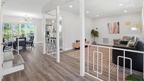 En moderne, åben planløsning med spiseområde, køkken og en trappe til et andet niveau.