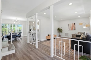 A modern open-plan living space with a dining area, kitchen, and a staircase leading to another level.
