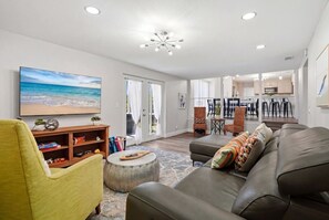 A modern living room with a sofa, armchair, and a flat-screen TV.