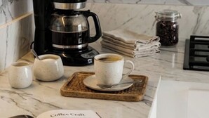A kitchen with a coffee maker, cups, a book, and a jar of coffee beans. - Large Central San Salvador Home - Near Downtown, A/C, WiFi, Parking & Netflix (San Salvador Department)