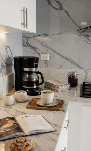 Eine Küche mit einer Kaffeemaschine, Tassen, einem Buch und einer Kaffeebohnen-Glaseinsatz.