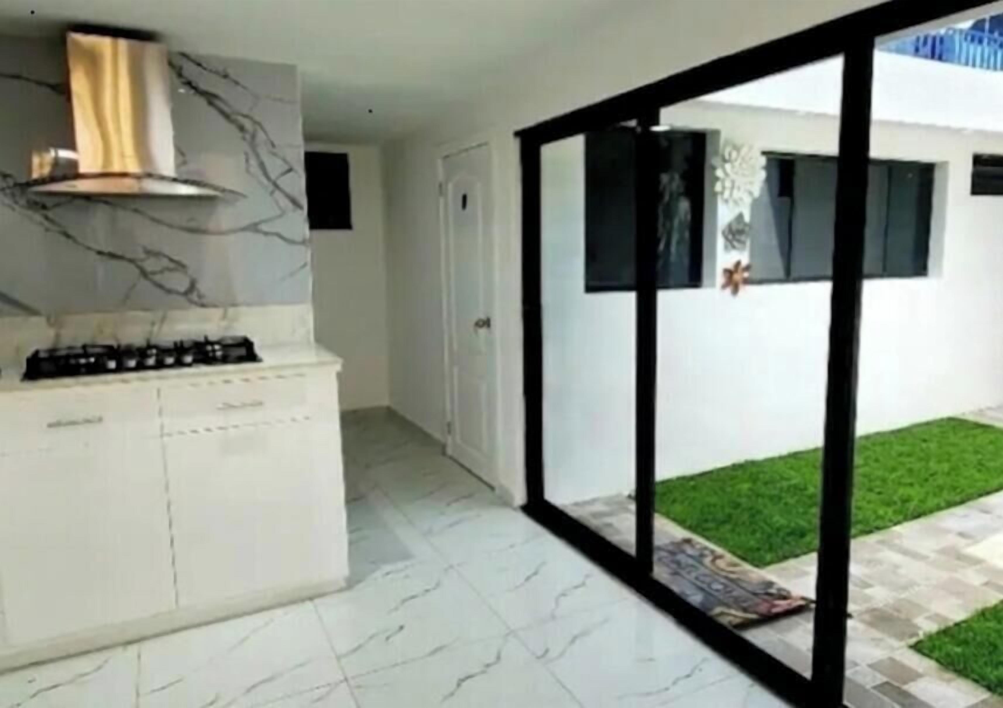 Une cuisine moderne dotée d’une cuisinière à gaz, de meubles blancs et d’un dosseret en marbre.