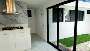 A modern kitchen with a gas stove, white cabinets, and a marble backsplash. - Large Central San Salvador Home - Near Downtown, A/C, WiFi, Parking & Netflix (San Salvador Department)