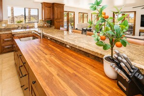 A kitchen with wooden cabinets, a granite countertop, and a potted plant with oranges. - The Villa at Fountain Hills | Pool, Hot Tub, Game Room, Ping Pong & Sleeps 20 (Fountain Hills)